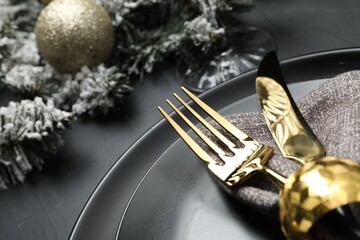 Plates, cutlery and Christmas decor on black table, closeup