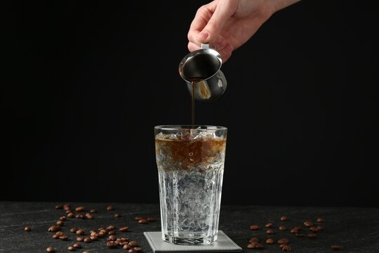 Woman making refreshing espresso tonic drink at dark table, closeup