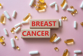 Breast cancer symbol. Wooden blocks with words Breast cancer. Beautiful pink background with pills....
