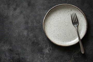 Bare round ceramic plate on dark concrete surface with cutlery ready for dinner
