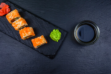 Sushi roll philadelphia with salmon, rice, cheese, cucumber, avocado and caviar on a slate board. Japanese food. Top view