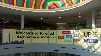 Naklejka premium Mississauga, ON, Canada - September 13, 2024: Multilingual “Welcome to Toronto” sign in Toronto’s Pearson International Airport in Mississauga, ON, Canada. Air Canada is Canada's largest airline.