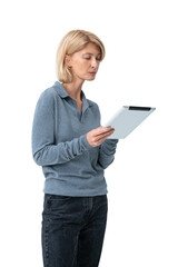 A woman in a blue sweater and jeans holding a tablet and looking at the screen, isolated on a white background. Concept of technology and focus © ImageFlow
