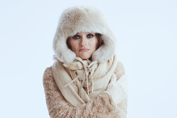 unhappy woman in winter coat and fur hat shivering on white