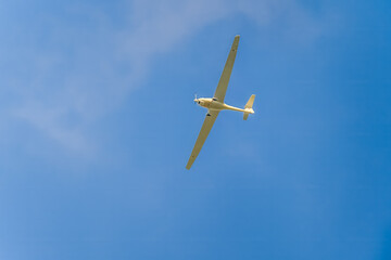 Glider with engine flying in blue sky