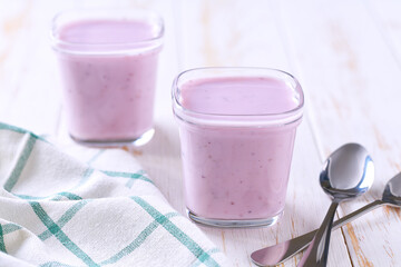 Homemade fruit smoothie in a glass jars with spoons on a rustic table, selective focus.