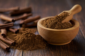 cinnamon powder in a wooden bowl  on a dark  wooden table, selective focus.