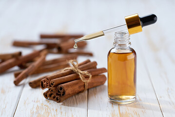 Essential aroma cinnamon oil with  on a white wooden table. Selective focus.