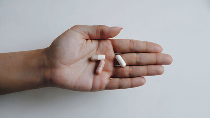Close-up of a Hand Holding Three Capsules on a Neutral Background