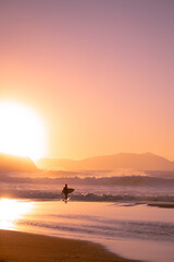 Fototapeta premium surfer with the board at sunset on the beach in the basque country