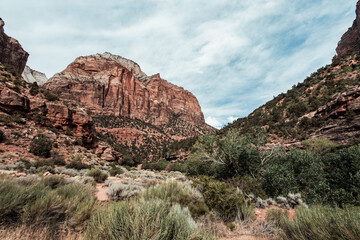 The majestic mountains of Zion National Park rise dramatically, their steep cliffs and vibrant red and orange hues contrasting against the clear blue sky.