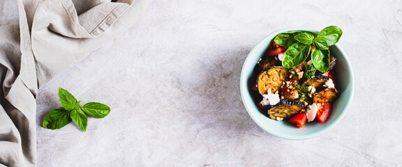 Vegetarian eggplant salad with tomatoes and cheese in a bowl top view web banner
