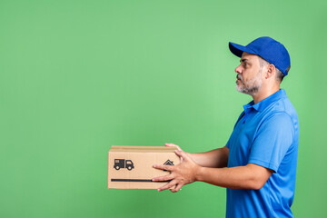 Side view of courier holding package, wearing blue uniform, on green screen background