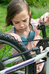 Obraz premium Young girl cyclist enjoy the beautiful sunrise on summer forest trail. Close-up portrait of a happy little girl in a helmet on a bicycle. High quality photo