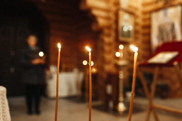 Three Tall Candles Glimmer During a Baptism Ceremony in a Wooden Church