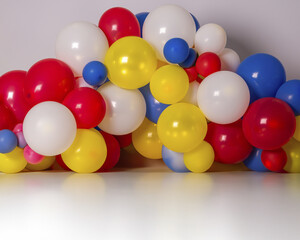 Fondo o atrezo con globos de color blanco, rosa, azul, verde, amarillo y rojo, cubriendo pared y piso blanco de ciclorama, para celebración, festividad, cumpleaños