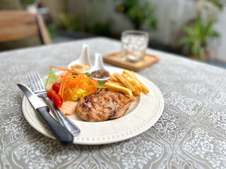 Chicken steak served alongside vibrant salad and crispy French fries. Chicken steak with French fries and a side of salad provides a nutritious and satisfying meal.