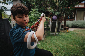 A young girl confidently handles colorful snakes in a lush garden, showcasing her fearless...