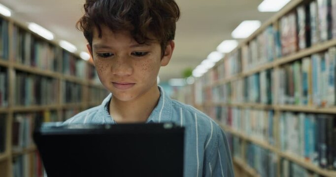 Tablet, child and student in library for reading, education or or learning information for knowledge. Technology, boy and kid walking to school for studying with ebook for math test preparation app