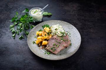 Cooked roast veal with sour cream sauce and roast potatoes served as close-up on a Nordic design...