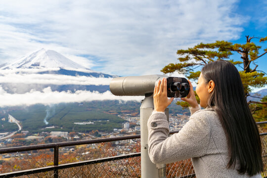 Asian woman enjoy outdoor lifestyle travel Japan on autumn holiday vacation. Attractive girl tourist travel lake Kawaguchi with using binoculars to look beautiful mt Fuji covered in snow on winter