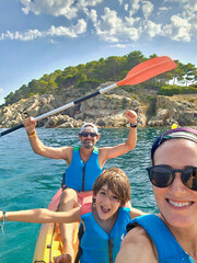 Family of three enjoying kayak activity at "la Fosca" Beach, one of the most amazing spots of "Costa Brava" Seaside in the Mediterranean sea, Catalonia, Spain.