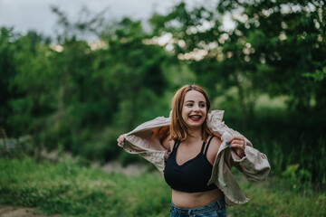 Obraz premium Happy woman with braces smiling joyfully in a green park. She appears carefree and cheerful, enjoying a casual outdoor moment.