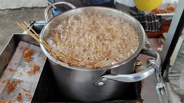 A chicken sempol seller is frying chicken sempol in hot oil, Sempol ayam is traditional chicken nuget from Indonesia.