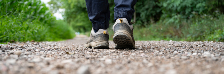 Wide view image of male legs walking on a gravel path in a journey through nature