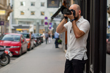 Bald and bold man taking pictures on the street in the city