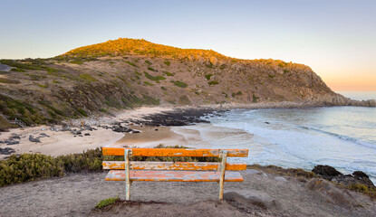 Obraz premium Bench at the Petrel Cove lookout with Rosetta Head or The Bluff on the Fleurieu Peninsula in South Australia at sunset