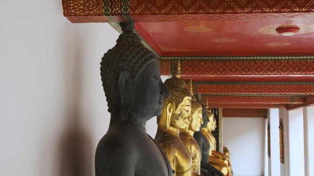 Black Buddha in a row of golden Buddha statues in Wat Pho Temple Complex in Bangkok city, Thailand, Asia. Temple of the Reclining Buddha. Popular travel landmark