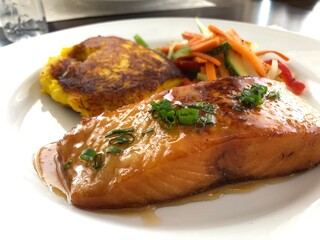 A delicious cut of salmon accompanied by polenta and sautéed vegetables
