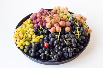 A bunch of various, freshly harvested grapes in a black metal tray