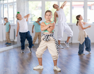 Fototapeta premium Positive cheerful smiling children studying modern style dance in light class indoors with male teacher