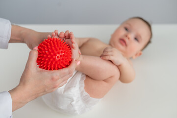 A doctor massages a baby's foot using a spiked ball.