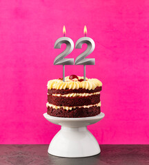 Birthday cake with number 22 candle - Red velvet on a fuchsia background.