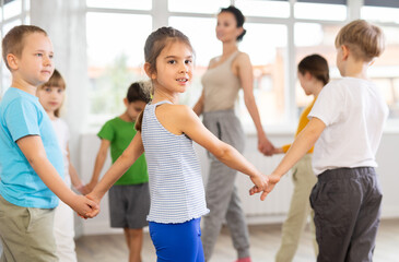 Group of boys and girls with teacher dancing traditional round dance in studio
