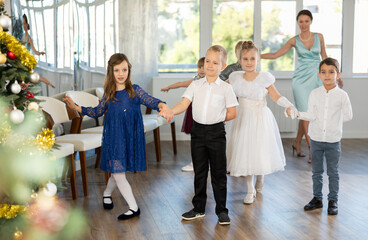 Pleased minor schoolboys and schoolgirls standing in row performing dance position in events salon...