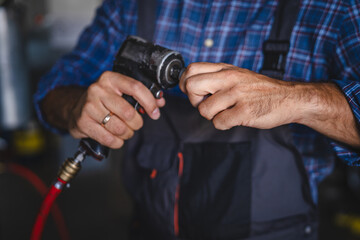 Close up of car mechanic hand hold power tool to repair car wheel