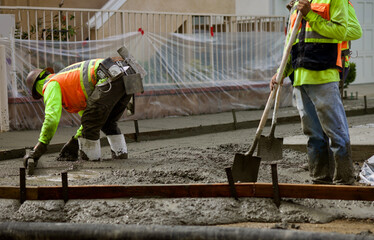 road construction worker spreading concrete with shovel