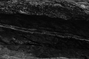Black and white beach with a huge rock and sea waves. Rock and stone texture