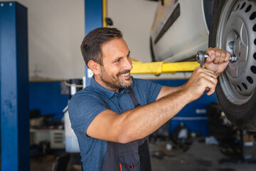 Car mechanic skillfully adjusting tire in modern auto repair shop