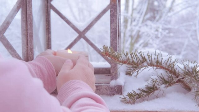 Christmas tree decoration, soft flame first Advent candle flickers inside garden lantern with snow gently falling in background for wintery feel, cozy Christmas scene