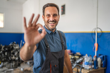 Car mechanic making okay gesture near car with friendly smile