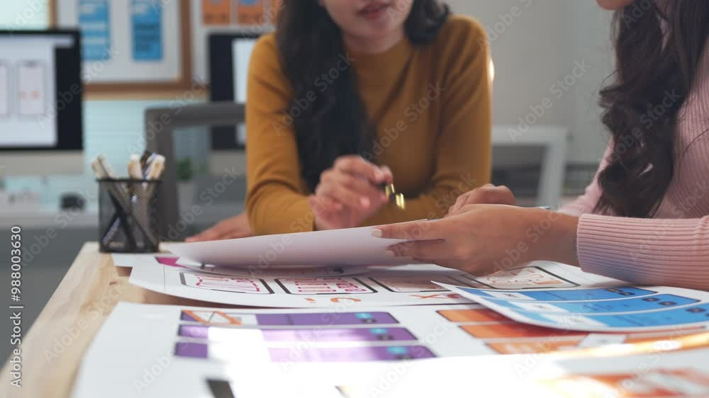 Aufkleber two ux designers engage in a discussion about mobile application interface sketches laid out on a de