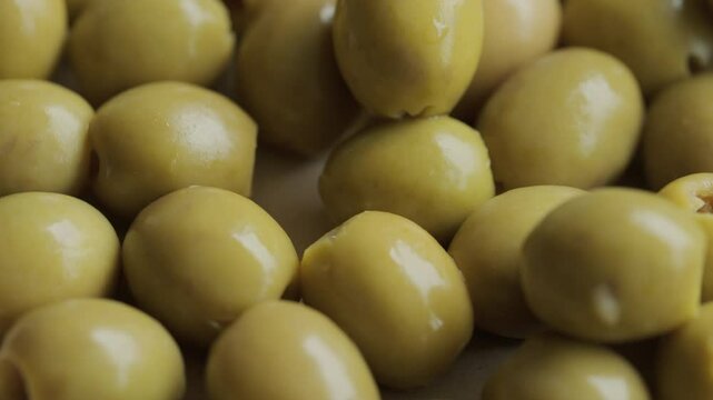 Green pitted olives background rotating macro. Mediterranean cuisine. Healthy eating.