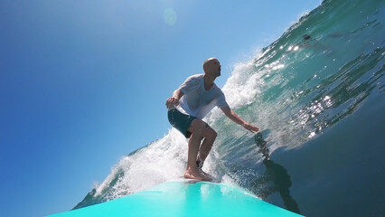 Man surfing a glassy wave on a blue board