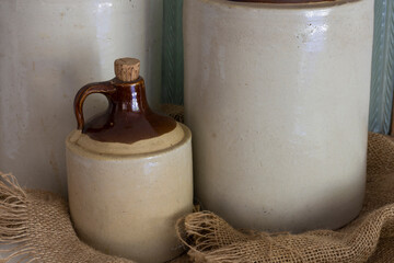 An image of three vintage ceramic whiskey jugs on a burlap cloth. 