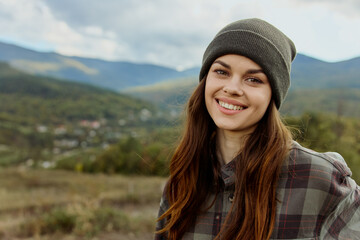 A woman in a stylish plaid shirt and beanie exploring the majestic mountains during a travel...